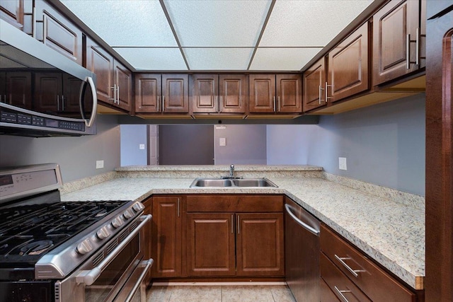 kitchen featuring dark brown cabinetry, a drop ceiling, stainless steel appliances, light countertops, and a sink