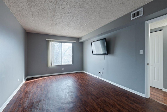 unfurnished room with dark wood-style floors, baseboards, and visible vents