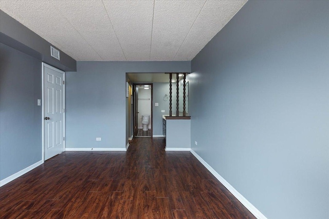 empty room with baseboards, visible vents, and dark wood-style flooring