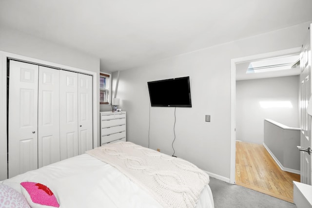 bedroom with baseboards, a closet, and light colored carpet