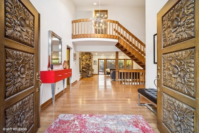 foyer entrance with baseboards, a high ceiling, a chandelier, and wood finished floors