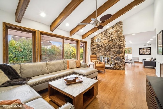 living room with beam ceiling, a fireplace, light wood finished floors, visible vents, and high vaulted ceiling