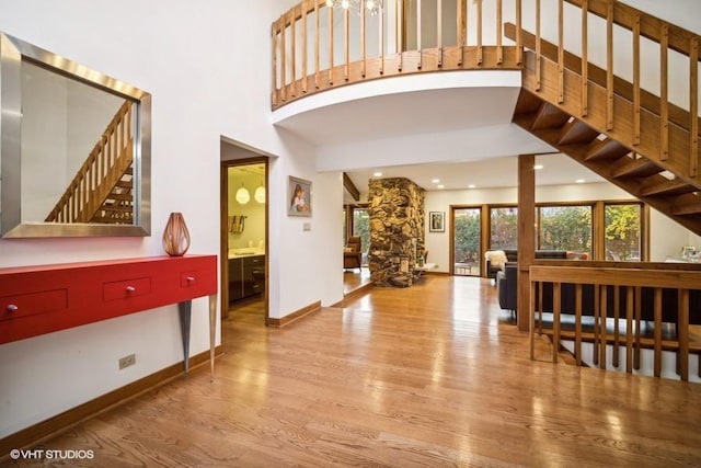 entryway with baseboards, a towering ceiling, wood finished floors, stairs, and recessed lighting