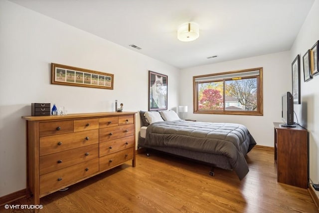 bedroom featuring wood finished floors and visible vents