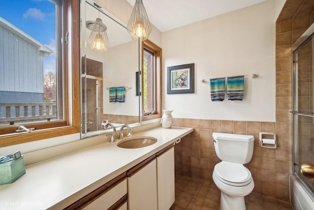 full bath featuring tile walls, toilet, wainscoting, vanity, and tile patterned flooring