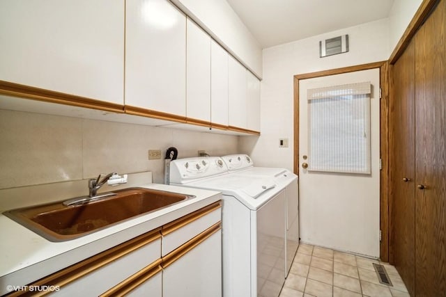 laundry area with cabinet space, light tile patterned floors, visible vents, washer and clothes dryer, and a sink