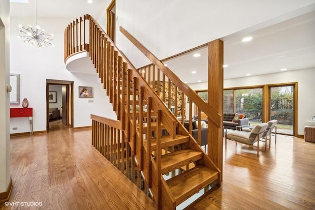 staircase featuring an inviting chandelier, baseboards, wood finished floors, and recessed lighting