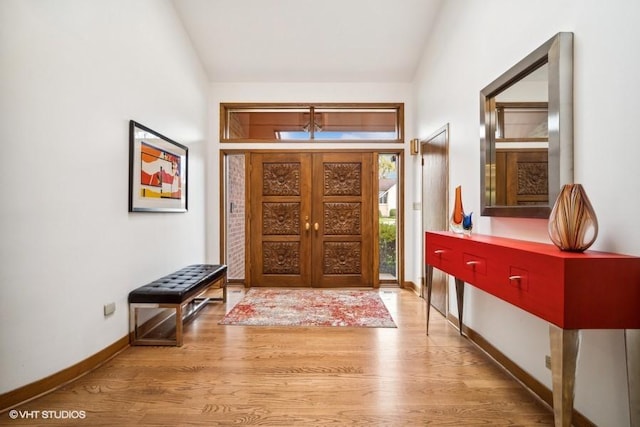 foyer entrance featuring vaulted ceiling, wood finished floors, and baseboards