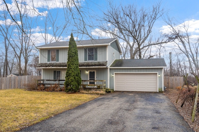 traditional home with aphalt driveway, a front lawn, an attached garage, and fence