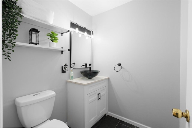 bathroom featuring toilet, tile patterned flooring, vanity, and baseboards