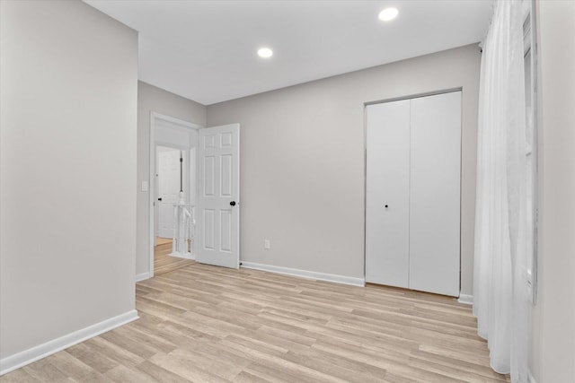 unfurnished bedroom featuring baseboards, a closet, recessed lighting, and light wood-style floors