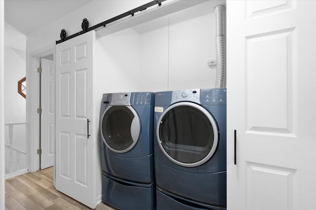 laundry area featuring laundry area, a barn door, light wood-type flooring, and washer and dryer