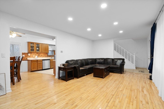 living room with ceiling fan, light wood finished floors, stairway, and recessed lighting