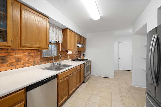 kitchen with stainless steel appliances, brown cabinets, light countertops, and a sink