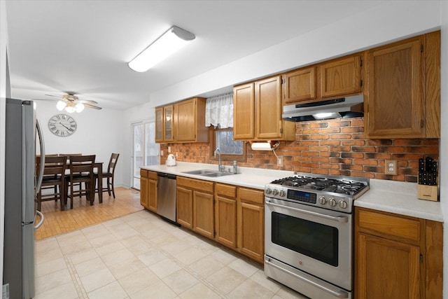 kitchen with a sink, under cabinet range hood, stainless steel appliances, and light countertops