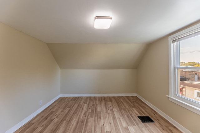 additional living space with light wood-type flooring, a wealth of natural light, visible vents, and baseboards