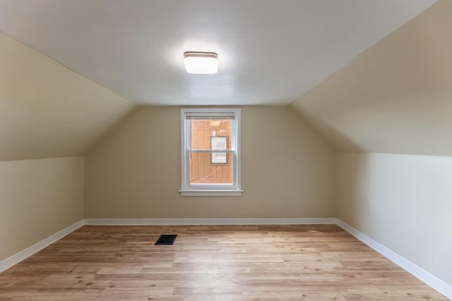 bonus room featuring light wood-type flooring, visible vents, lofted ceiling, and baseboards