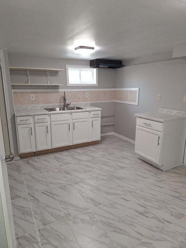 kitchen featuring marble finish floor, open shelves, a sink, and white cabinets