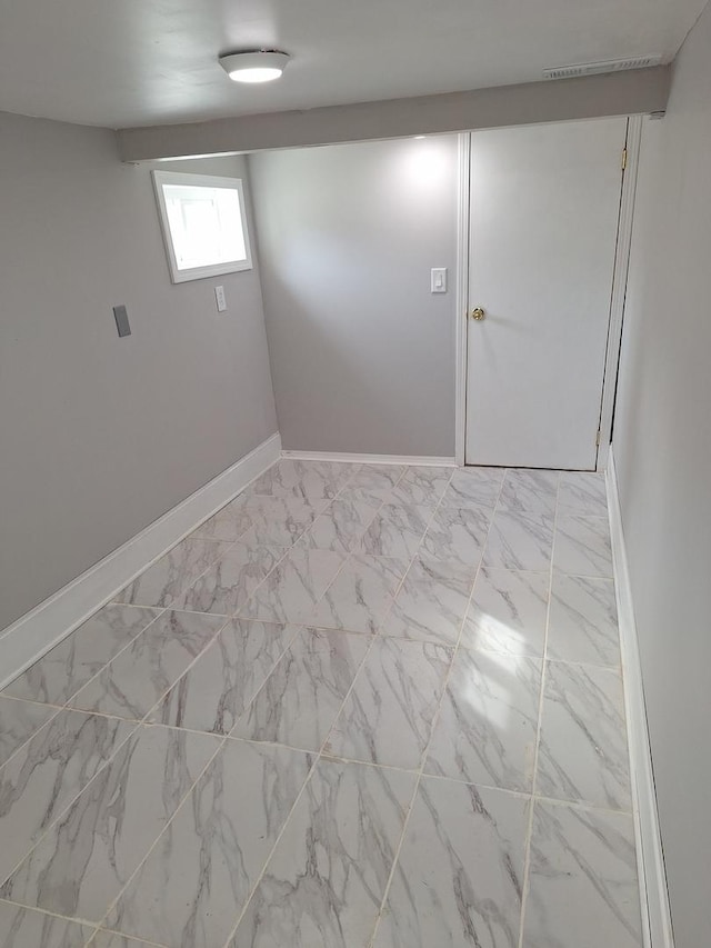 basement featuring marble finish floor and baseboards