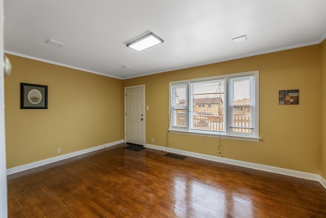 spare room with baseboards, visible vents, dark wood finished floors, and crown molding