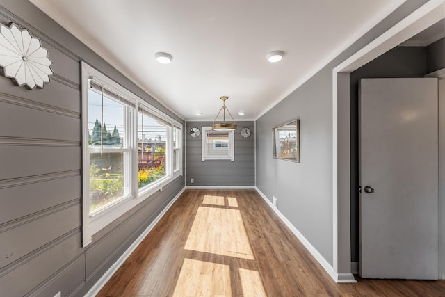 unfurnished dining area with visible vents, baseboards, wood finished floors, and ornamental molding