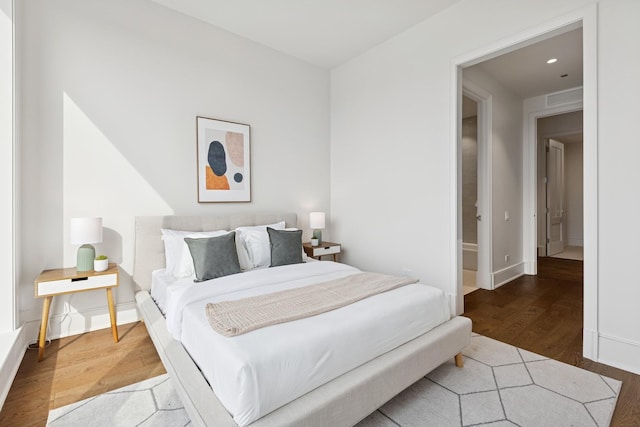 bedroom with baseboards, visible vents, and wood finished floors