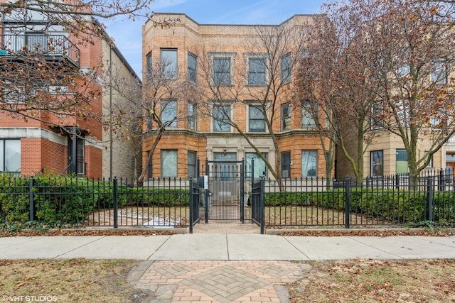 view of property with a fenced front yard, a gate, and brick siding