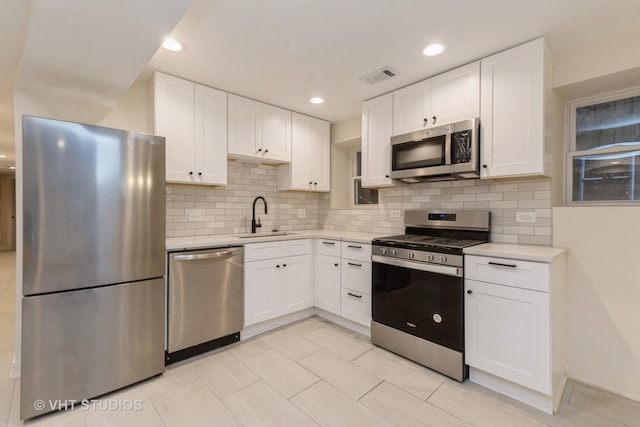 kitchen with visible vents, white cabinets, stainless steel appliances, light countertops, and a sink