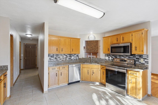 kitchen featuring light tile patterned floors, a sink, stainless steel appliances, stone counters, and backsplash