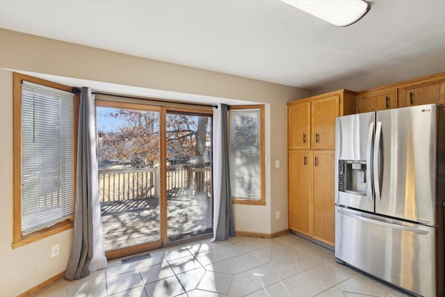 kitchen featuring visible vents, stainless steel refrigerator with ice dispenser, baseboards, and light tile patterned floors