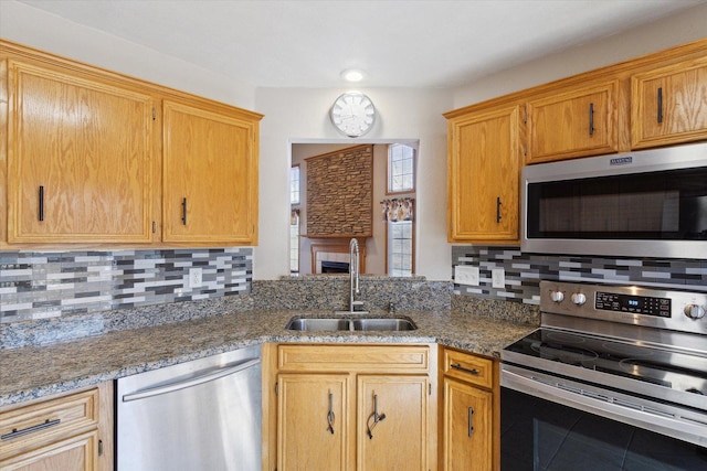 kitchen featuring stainless steel appliances, stone countertops, a sink, and tasteful backsplash