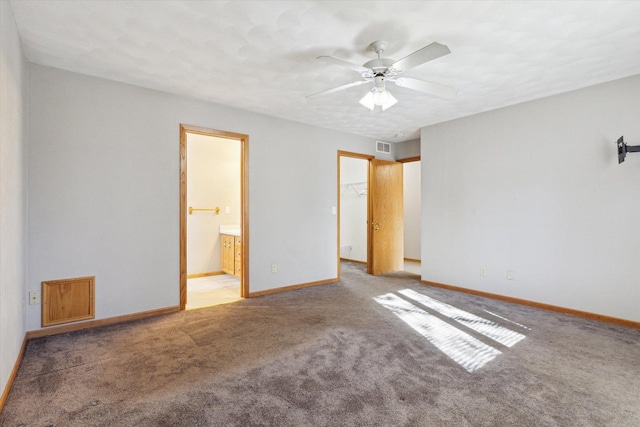 unfurnished bedroom featuring carpet floors, ensuite bath, baseboards, and visible vents