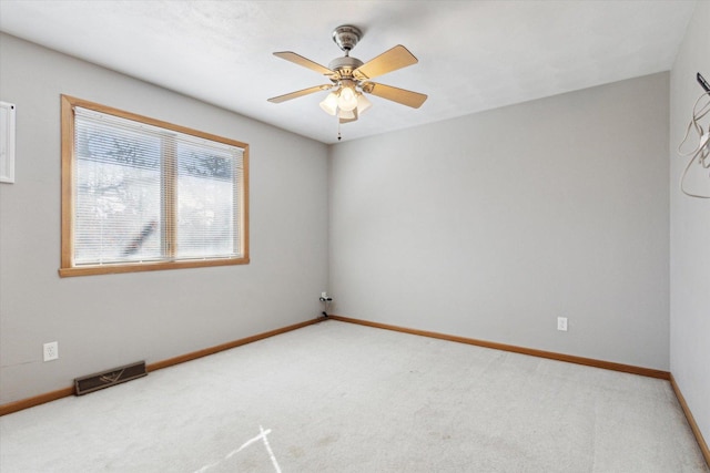 carpeted spare room featuring a ceiling fan, visible vents, and baseboards