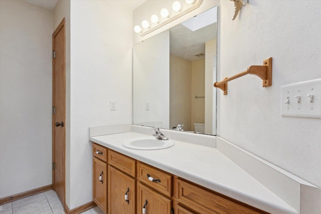 bathroom featuring visible vents, toilet, vanity, baseboards, and tile patterned floors