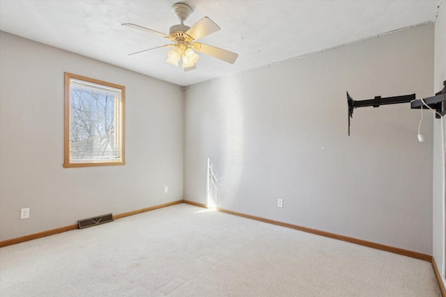 carpeted spare room with baseboards, visible vents, and a ceiling fan