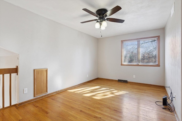 empty room with a ceiling fan, light wood-type flooring, visible vents, and baseboards