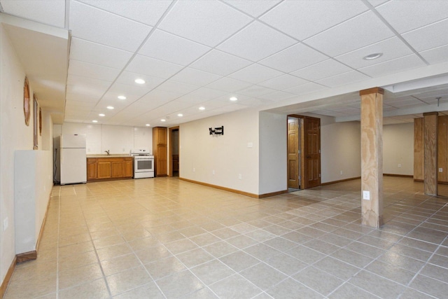 interior space featuring a paneled ceiling, recessed lighting, freestanding refrigerator, light tile patterned flooring, and baseboards