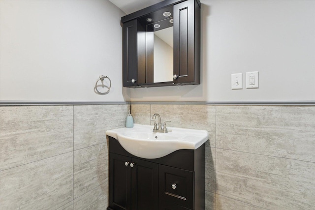 bathroom featuring a wainscoted wall, vanity, and tile walls