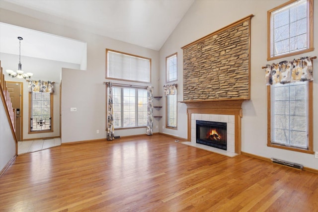 unfurnished living room featuring high vaulted ceiling, a tile fireplace, visible vents, and light wood-style floors