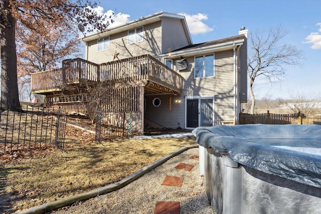 rear view of house with a chimney, fence, and a deck