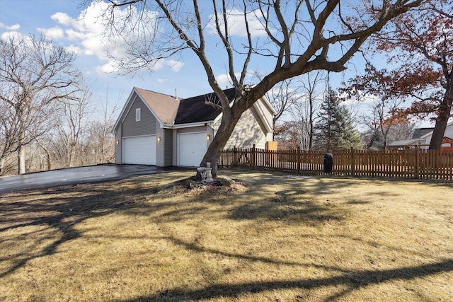 view of side of home with a garage, brick siding, fence, driveway, and a yard