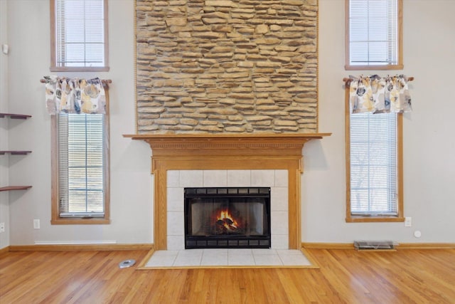 details with baseboards, a fireplace, visible vents, and wood finished floors