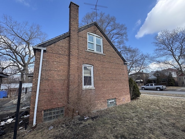 view of side of property with a chimney and brick siding