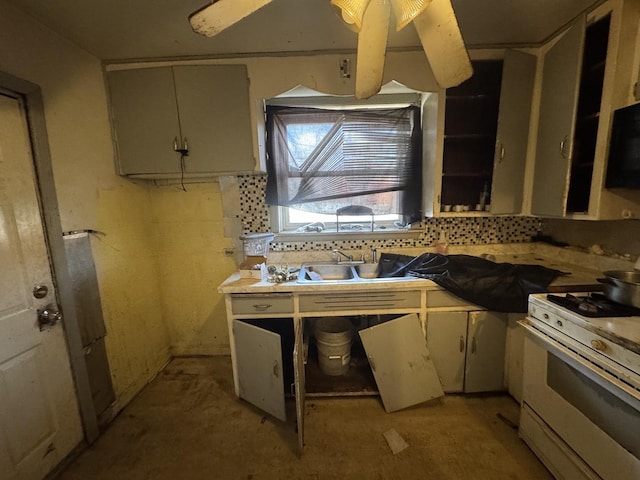 kitchen featuring a sink, backsplash, gas range gas stove, and light countertops