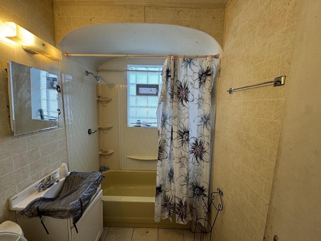 full bathroom with vanity, shower / bath combo with shower curtain, tile walls, and tile patterned floors