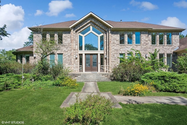 view of front of house with french doors, a front yard, and brick siding