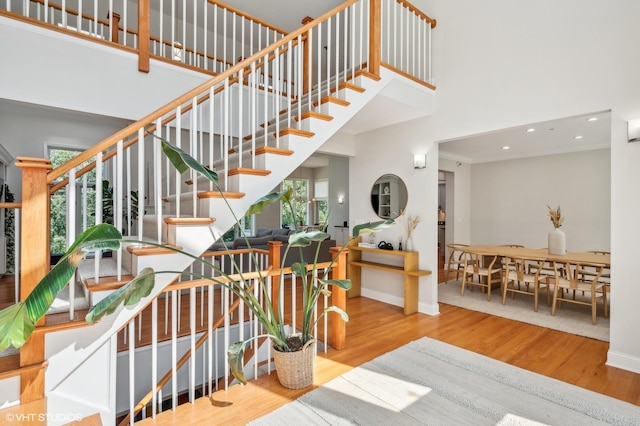 stairs with a high ceiling, recessed lighting, wood finished floors, and baseboards