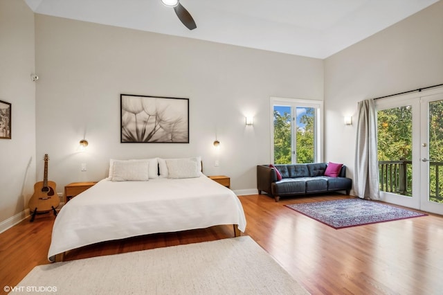 bedroom with access to outside, wood finished floors, and baseboards