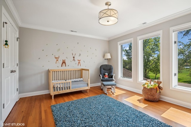 unfurnished bedroom featuring ornamental molding, multiple windows, wood finished floors, and visible vents