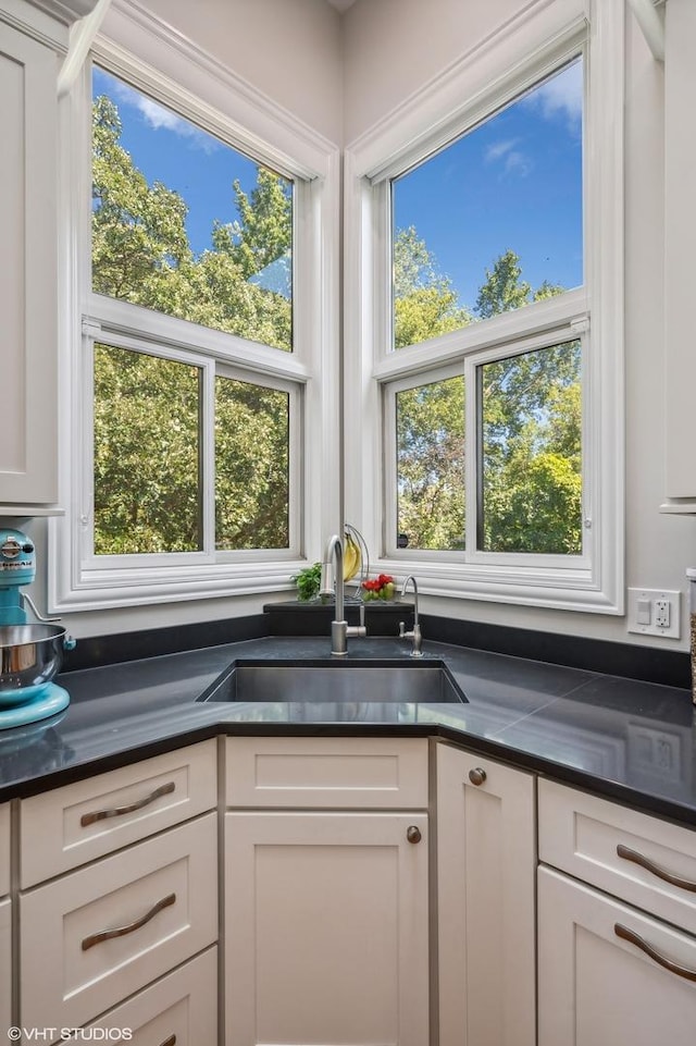 kitchen with dark countertops, a sink, and white cabinets